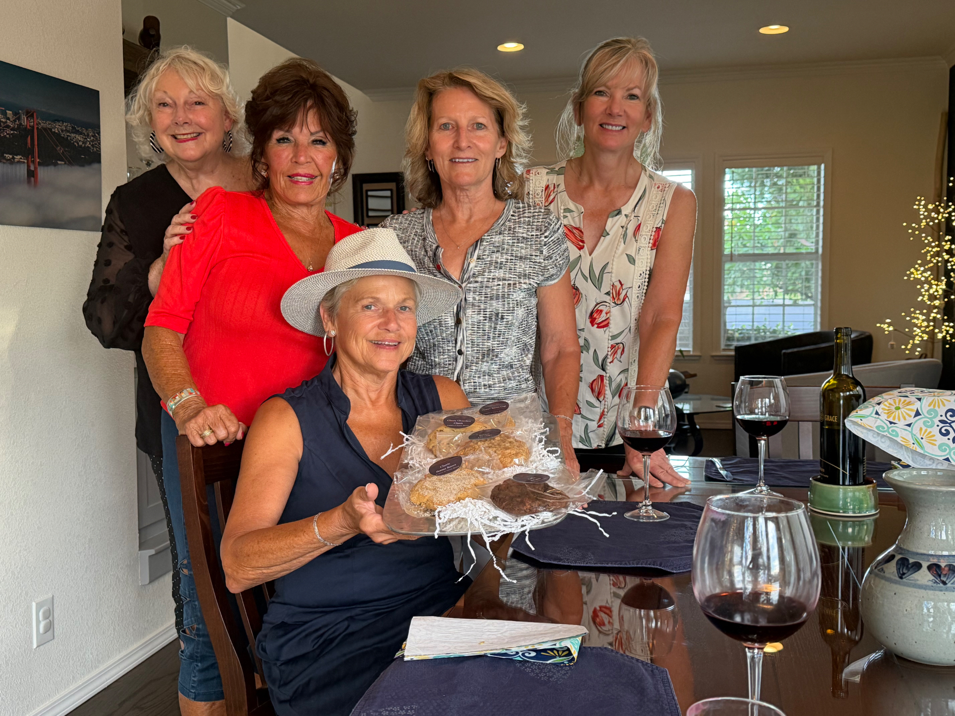 Friends gathered around a table sharing a box of Angie's cookies